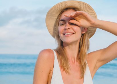 A woman sitting on the beach wearing a sunhat