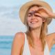 A woman sitting on the beach wearing a sunhat