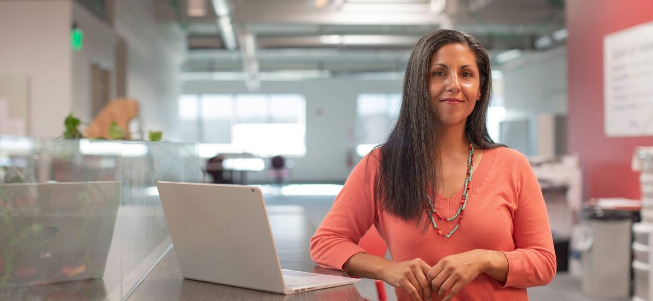 A smiling female business owner standing next to a laptop computer