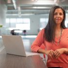 A smiling female business owner standing next to a laptop computer