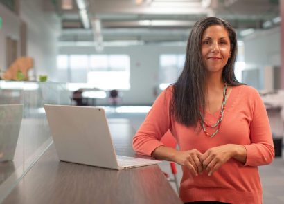 A smiling female business owner standing next to a laptop computer