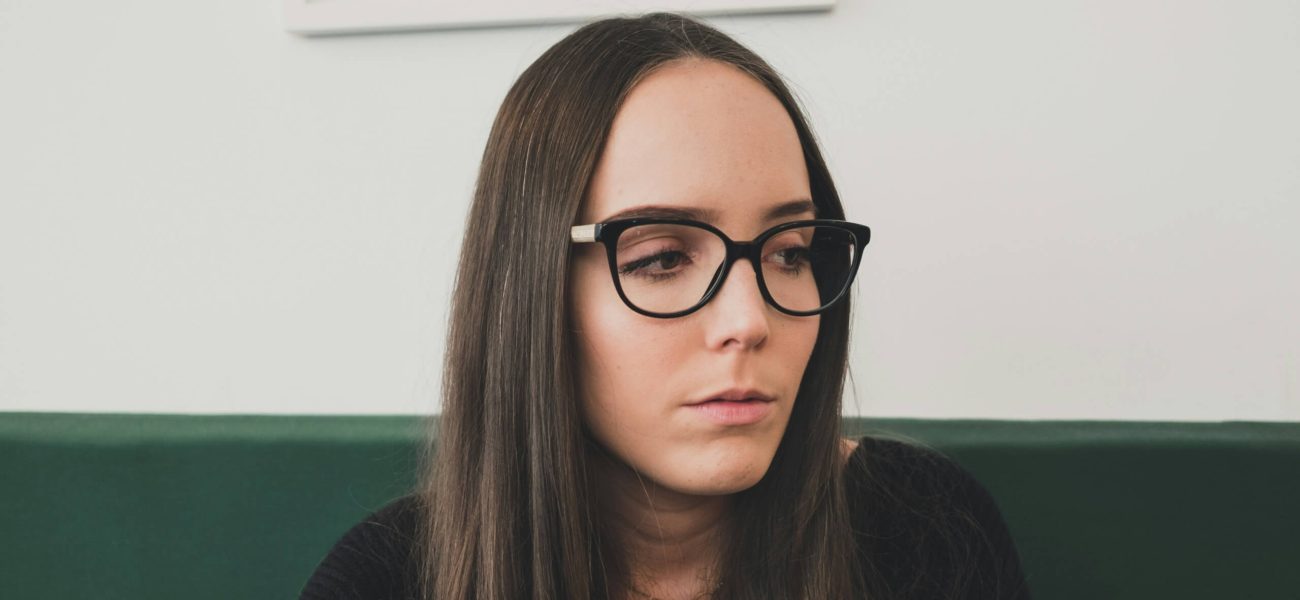 A brown-haired woman with glasses looking concerned