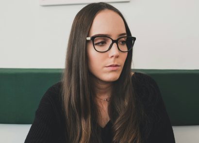 A brown-haired woman with glasses looking concerned