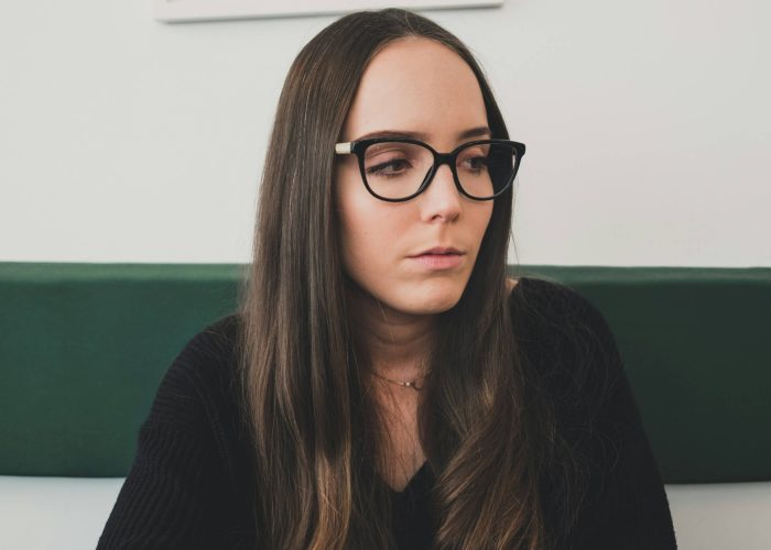 A brown-haired woman with glasses looking concerned