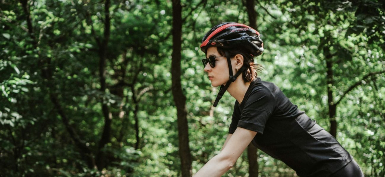 A woman riding through a forest on a racing bicycle