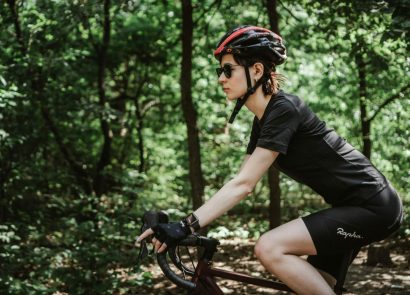 A woman riding through a forest on a racing bicycle