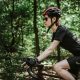 A woman riding through a forest on a racing bicycle
