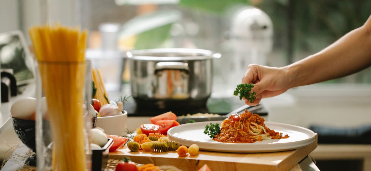 A chef serving a pasta dish in a home kitchen