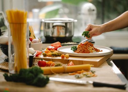 A chef serving a pasta dish in a home kitchen