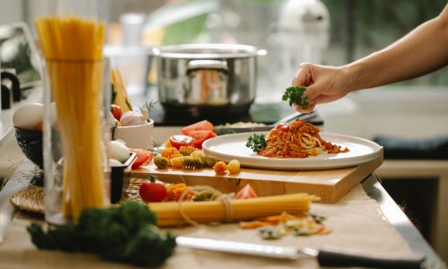 A chef serving a pasta dish in a home kitchen