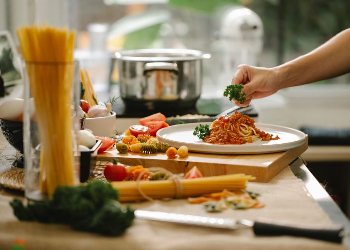 A chef serving a pasta dish in a home kitchen