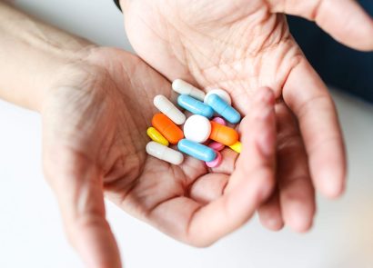 A woman's hands holding a variety of tablets and capsules