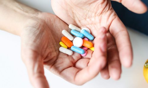 A woman's hands holding a variety of tablets and capsules