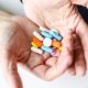 A woman's hands holding a variety of tablets and capsules
