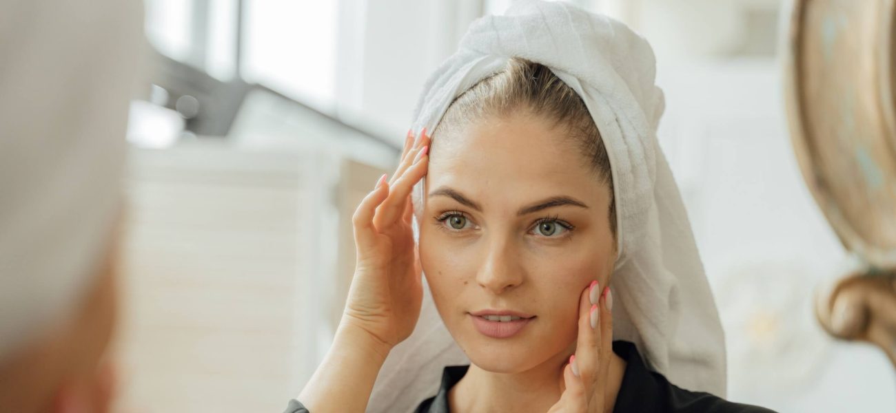 A woman with beautiful skin looking at herself in a bathroom mirror