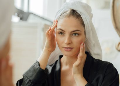 A woman with beautiful skin looking at herself in a bathroom mirror