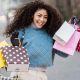 A smiling woman holding a selection of colourful shopping bags on a city street